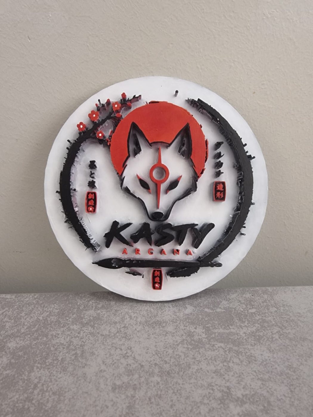 Medallón circular con el emblema de Kasty Arcana pintado a mano